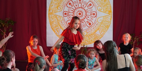 Powiększ grafikę: Na scenie młodzi artyści siedzą w kręgu i wirują wokół ogniska.